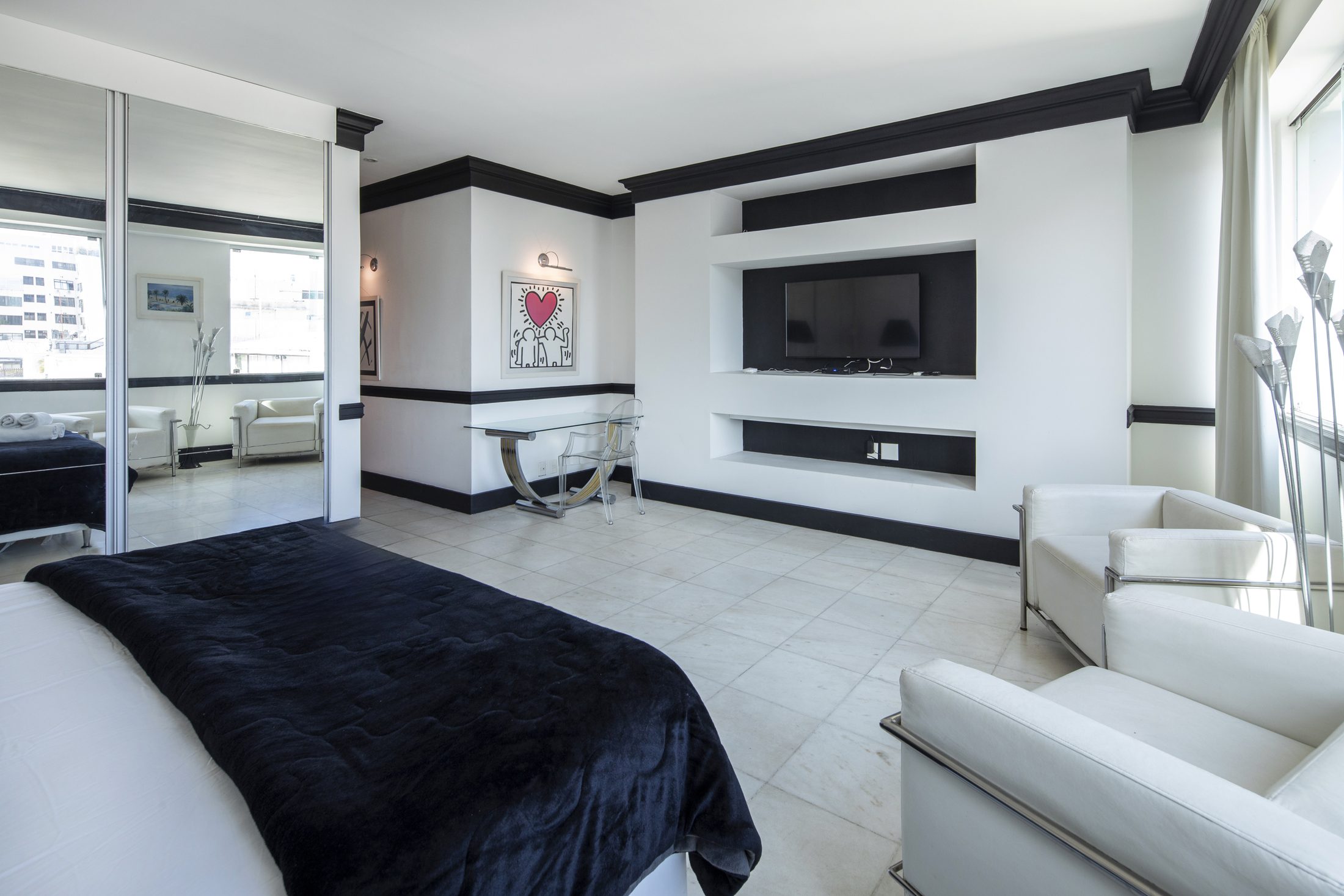 A black-and-white suite with a built-in TV wall and white armchairs